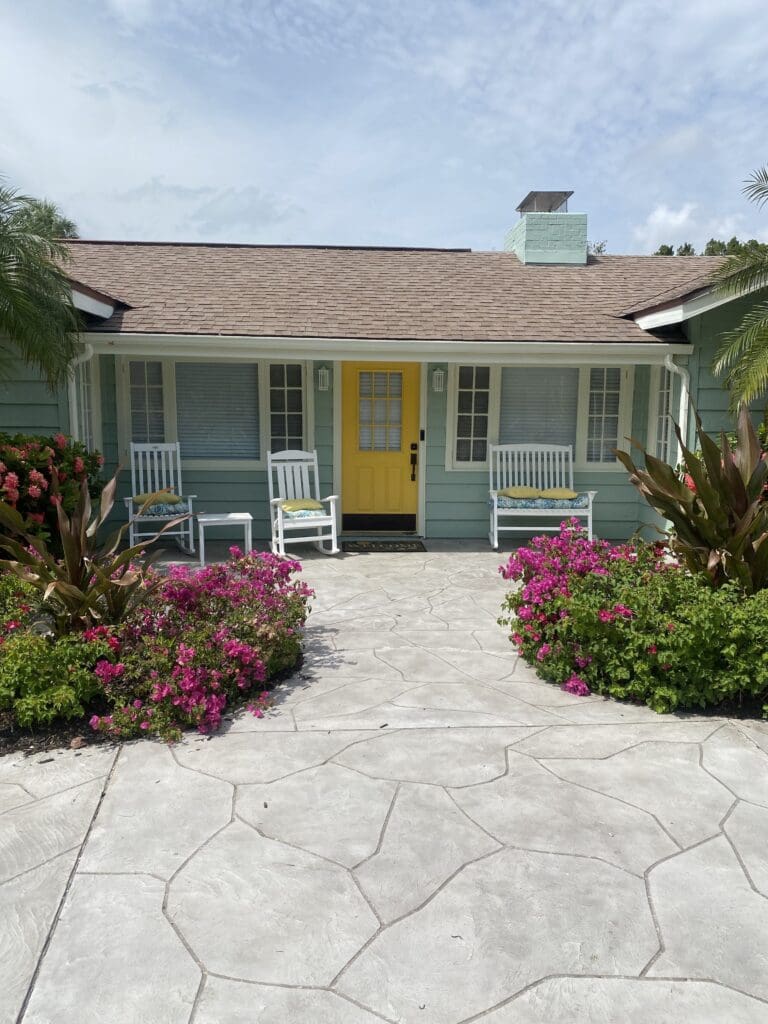 A house with a yellow door and white chairs.